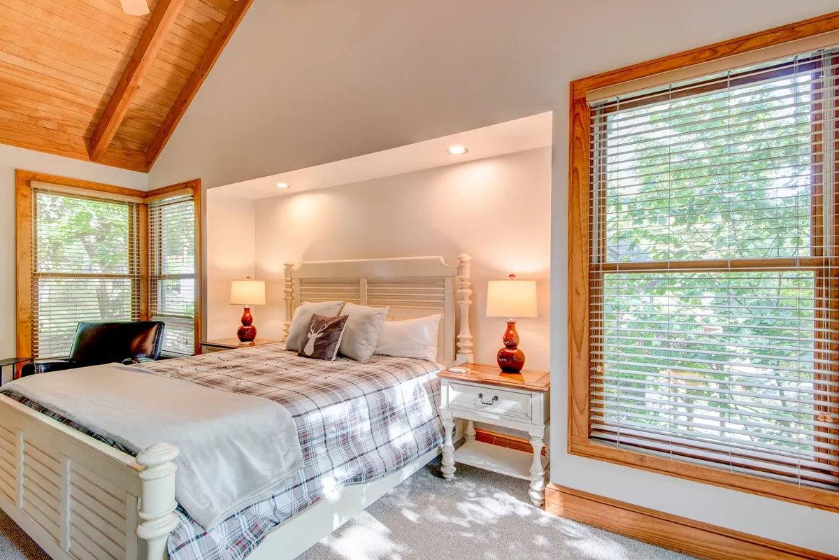 A tranquil bedroom with a comfortable bed, windows letting in gentle natural light, side tables with decorative lamps, and soft, neutral-toned bedding. The room radiates peace and relaxation, evoking an inviting atmosphere for restful sleep.