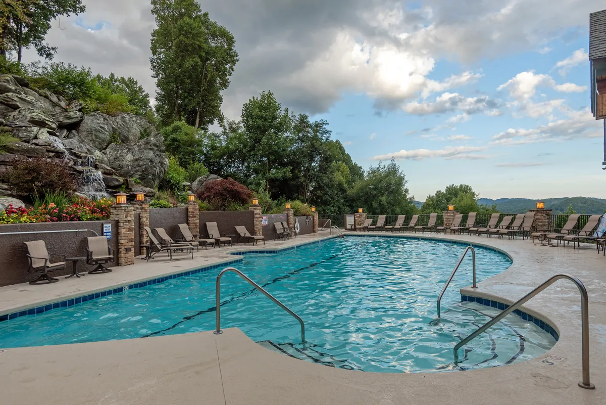 A sparkling swimming pool bordered by rock formations and lush landscaping, with comfortable lounge chairs inviting relaxation. The scene captures the fun and rejuvenation of poolside moments with scenic mountain surroundings.