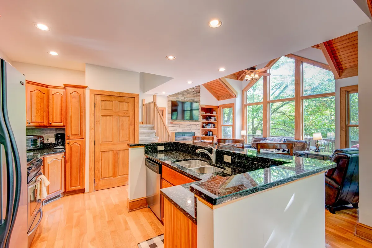 A closer view of the kitchen area, focusing on sleek granite countertops, rich wooden cabinetry, stainless steel appliances, and ample windows. The open layout is ideal for cooking, entertaining, and enjoying scenic views while preparing meals.